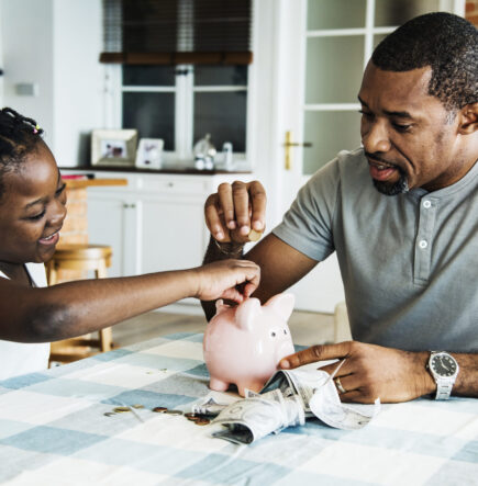 Dad and daughter saving money to piggy bank