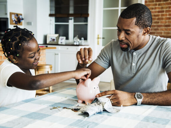 Dad and daughter saving money to piggy bank Dad and daughter saving money to piggy bank